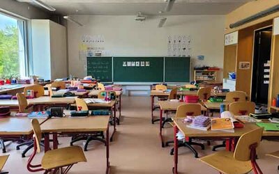 Ein Klassenzimmer mit vielen Tischen und Stühlen und einer grünen Tafel; Bild: Nathan Cima auf Unsplash